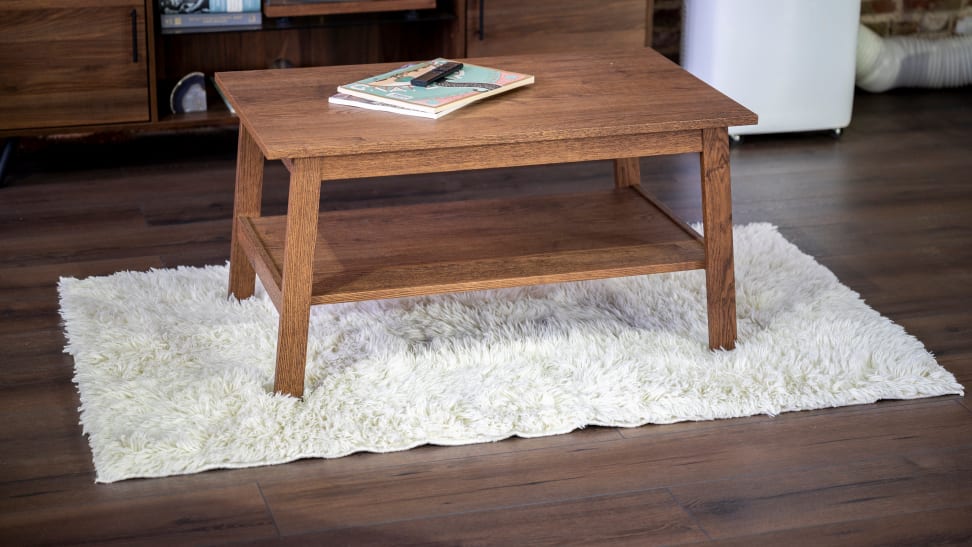 Rectangular white shag rug under wooden coffee table in living room.