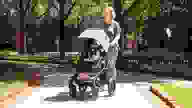 Woman walking in the park with the Bugaboo Fox 5 stroller in the color black.