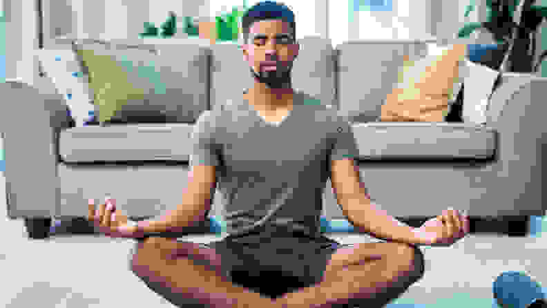 A man meditating in the living room.