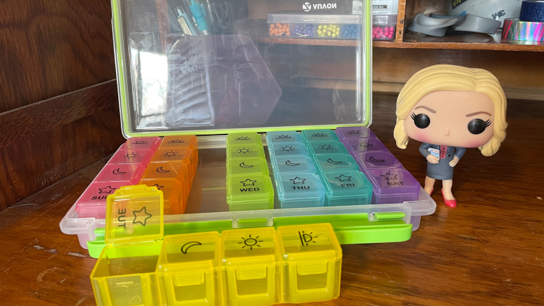 The Auvon iMedassist Moisture-Proof Weekly Pill Organizer next to a Funko Pop figurine