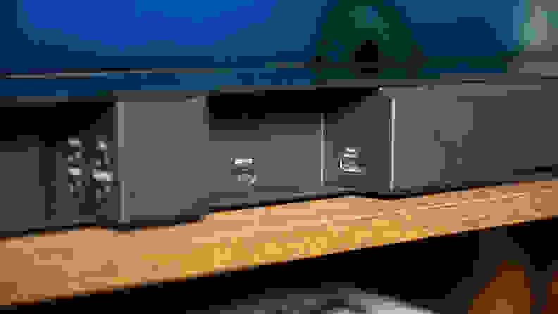 The back inputs section of a black soundbar reveals an multiple 3.5mm inputs including ports for bass, IR, data, and Adaptiq