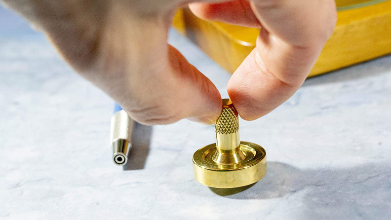 A hand spins a small gold top on a desk.