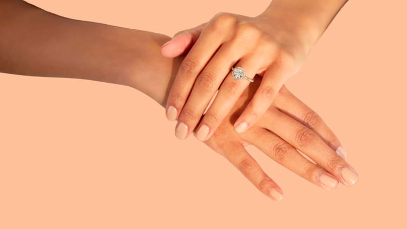 A diamond ring on a hand holding another hand.