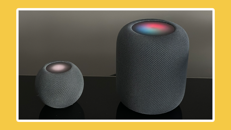 Apple HomePod mini and HomePod side by side on black surface.