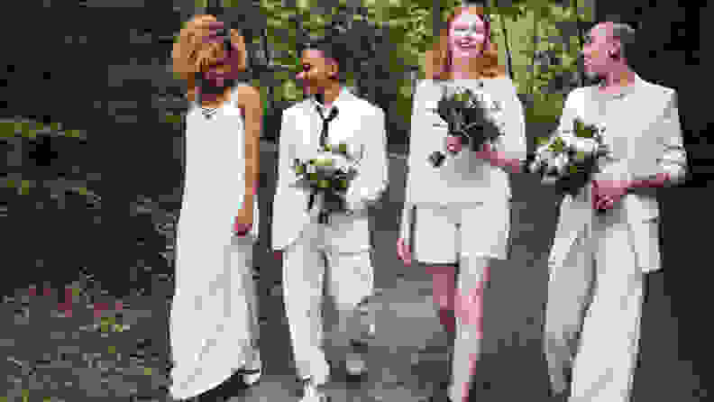 LGBT Wedding Celebration, four humans each dressed in white, one in a long dress, another in a skirt, and two in pants suits, holding bouquets.