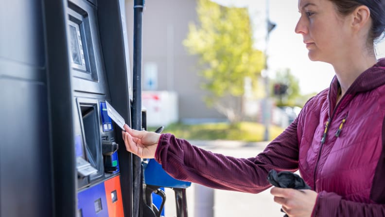 Person at gas pump using credit card.