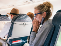 Person blowing nose on plane