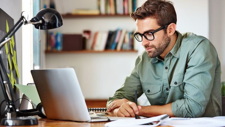 Une personne est assise à un bureau et travaille sur un ordinateur portable