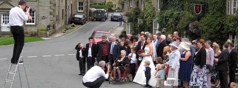 Two wedding photographers photographing a large wedding party.