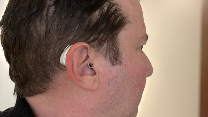 A hearing aid sits behind a man's ear as he gazes in profile