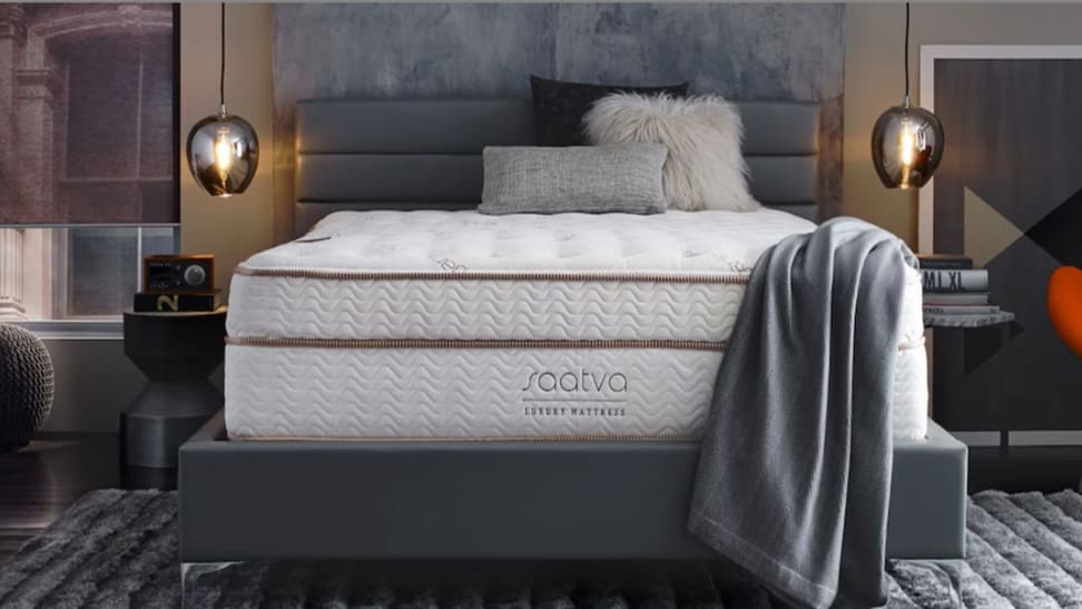 A Saatva Classic mattress without sheets on it in a bedroom setup.
