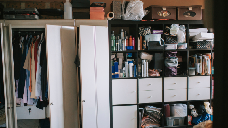 Walk-in closet cluttered with clothes and paperwork.