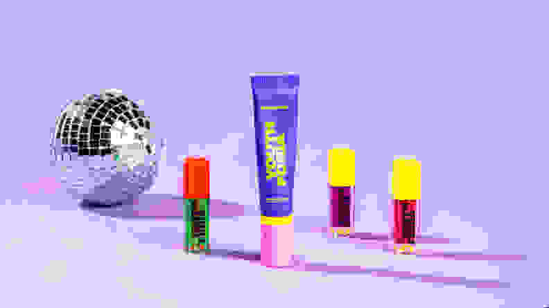A disco ball sits next to an array of four Youthforia products against a lavender background.