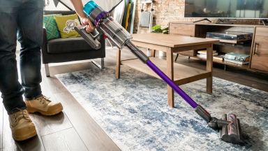 A person using the Dyson Gen5detect cordless vacuum to clean a rug.