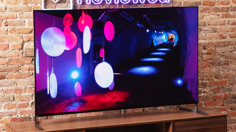 The Sony A95L on a home theater credenza displaying a colorful image.
