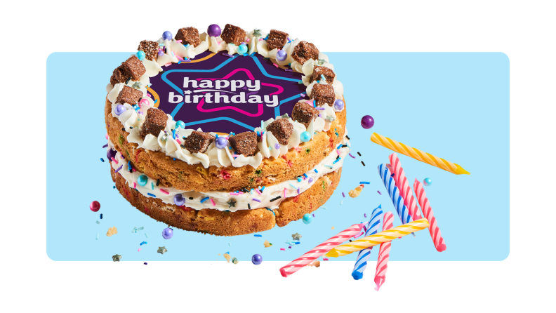 A double layer cookie birthday cake with "Happy Birthday" written on it in front of a background.