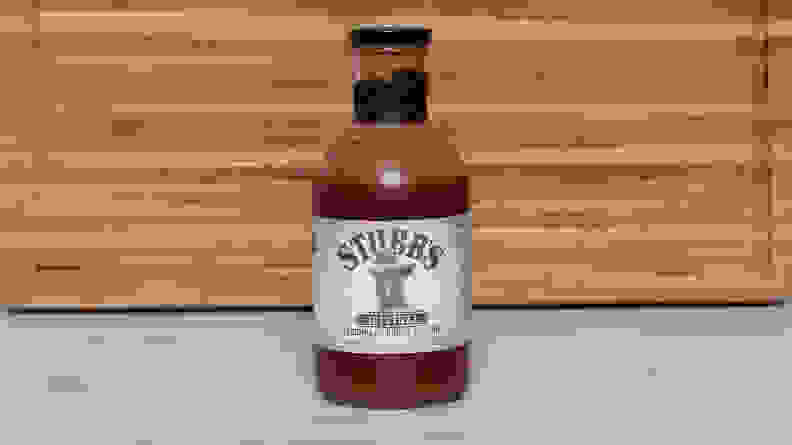 A bottle of Stubb’s Original Legendary Bar-B-Q sauce next to a wood cutting board.