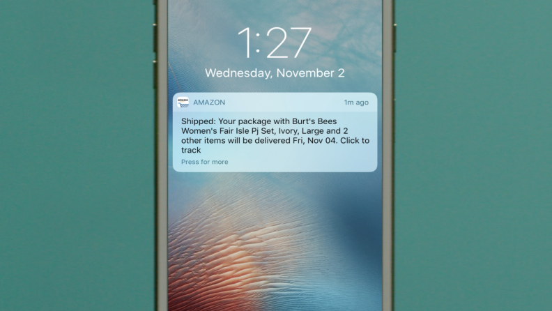 A person receives an order shipment update on their phone from Amazon