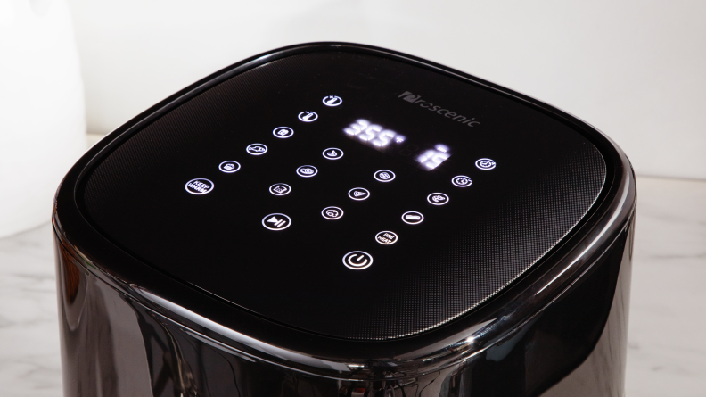 Person using fingers to press keypad buttons of the Proscenic T22 Air Fryer.