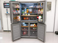 A four-door fridge completely open, showing all storage spaces filled with food.