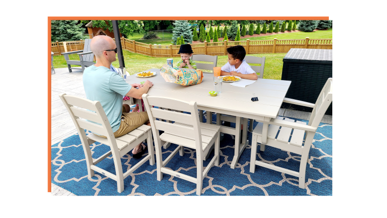 An adult and a child sit at a Polywood outdoor patio dinner table.