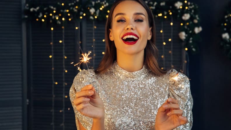 Woman wearing sparkly metallic dress while holding a sparkler.