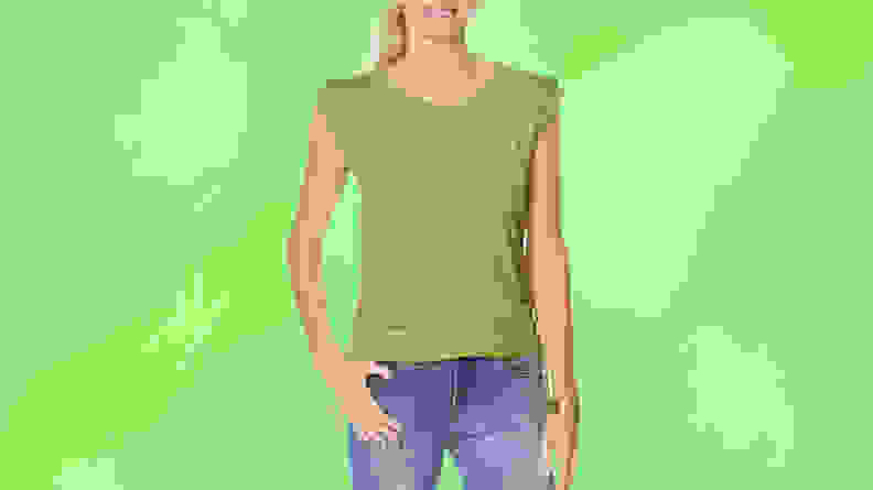 A woman wearing a green shirt and jeans in front of a green background.
