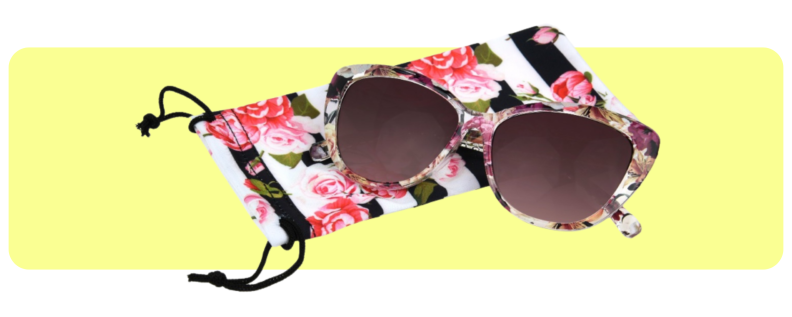 A pair of floral cat-eye sunglasses lays upon a floral carrying case.
