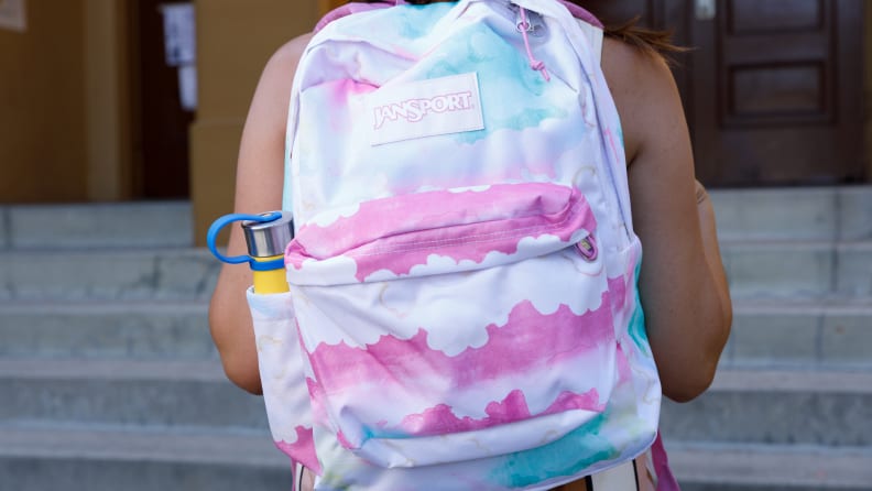 A tie-dye style school backpack worn by a girl.