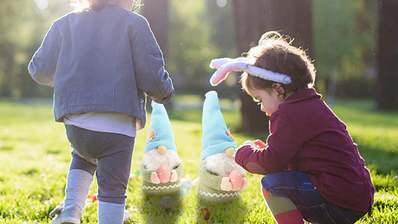 Two little girls standing near two gnomes