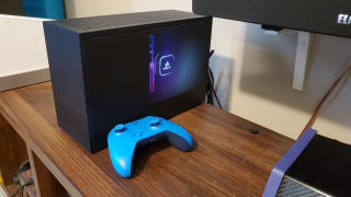 A PC case on a table, with a blue controller in front of it.