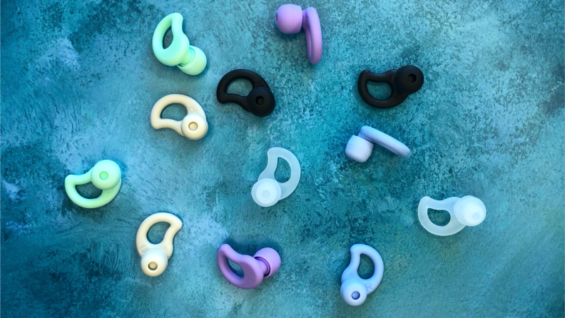 A range of CURVD earplugs in every color, laid out on blue fabric.