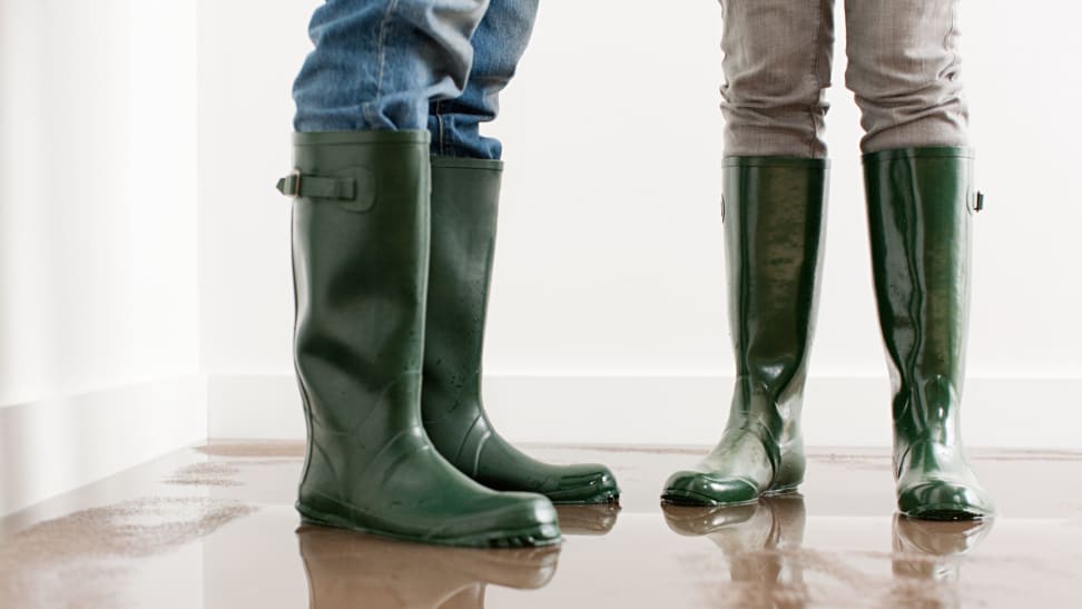 Two people in rubber boots standing on carpet covered in inches of water