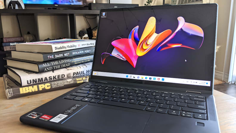 An open Lenovo Yoga 6 on a coffee table with a stack of books behind it.