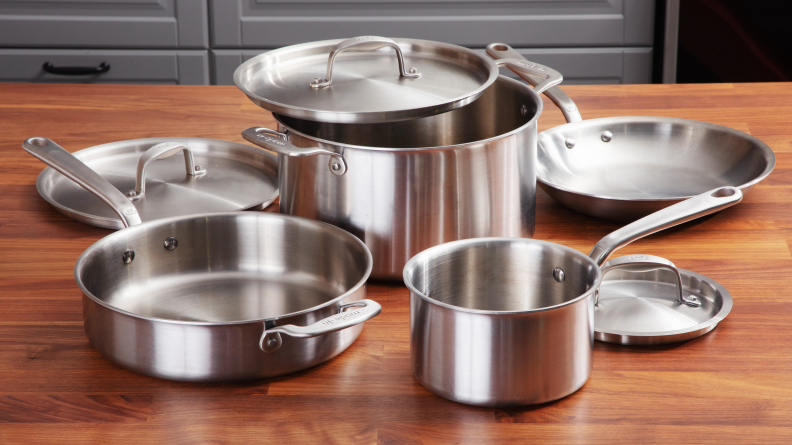 Various stainless steel pots and pans on wooden surface