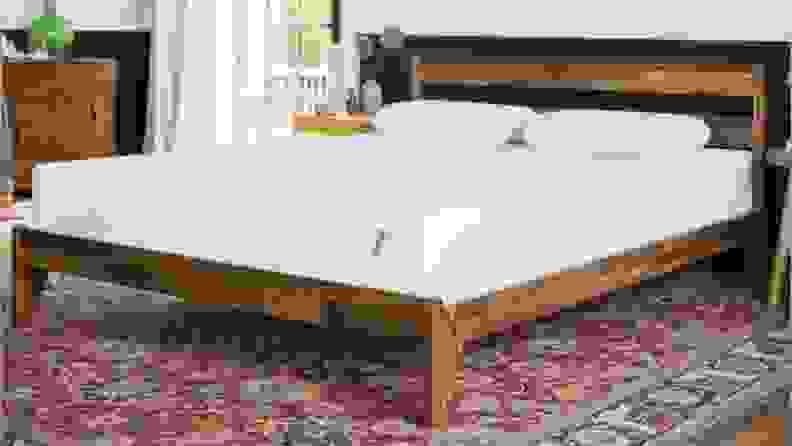 the Tuft & Needle original mattress on a brown wood bedframe with a pink carpet