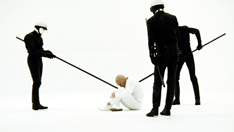 Android cops surround Robert Duvall, brandishing quarterstaffs, in the 1971 film THX 1138.