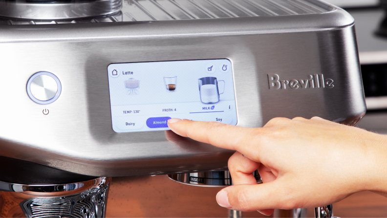 Person using finger to make dairy selection on the Breville Barista Touch Impress' touchscreen display.
