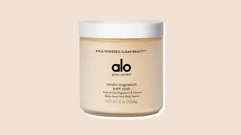 A tan container of Alo Yoga's Glow System Mindful Magnesium bath soak on a neutral background.
