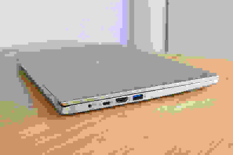 A side view of a closed laptop on top of a light brown wooden surface.