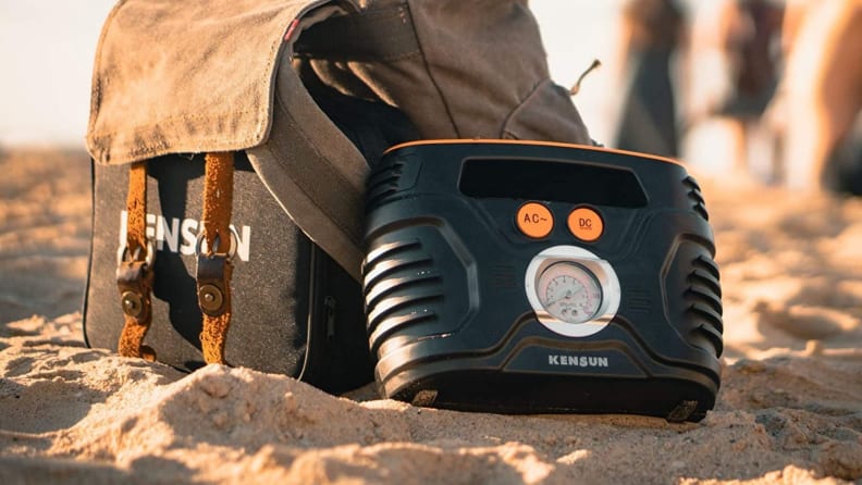 Portable air compressor on sandy beach with people in the distant background