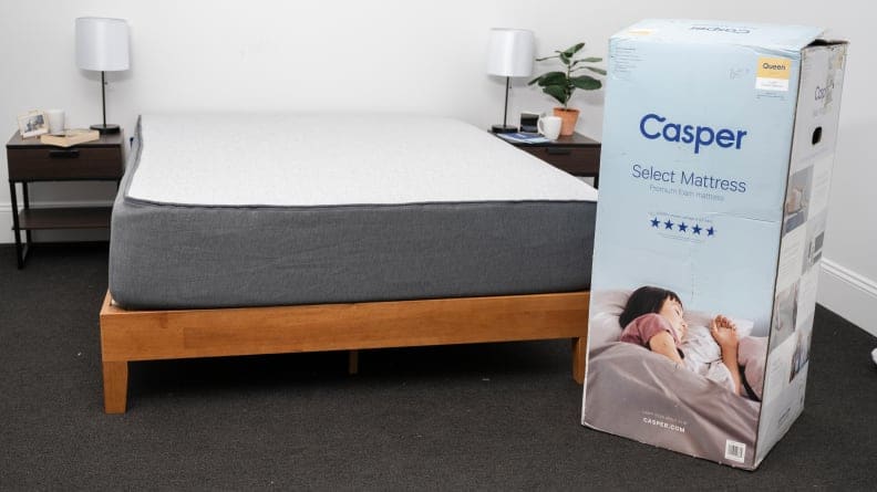 a mattress on a bed frame with a boxed mattress next to it