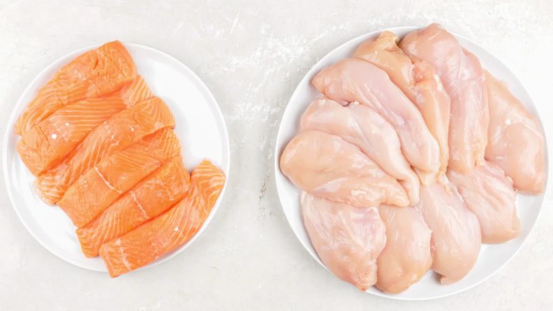 Two plates, one filled with salmon fillets and the other filled with chicken breasts.