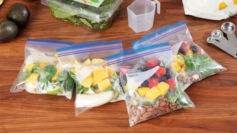 Four bags of smoothie ingredients on a wood counter.