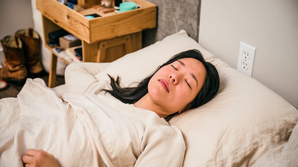 a person lies on their back asleep in bed