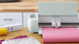 A Cricut machine set up on a table surrounded by supplies.