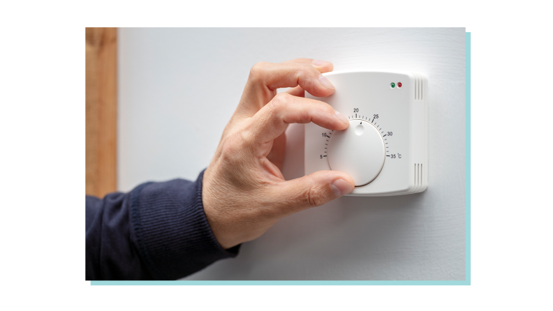 Person using hand to adjust temperature on thermostat in home.