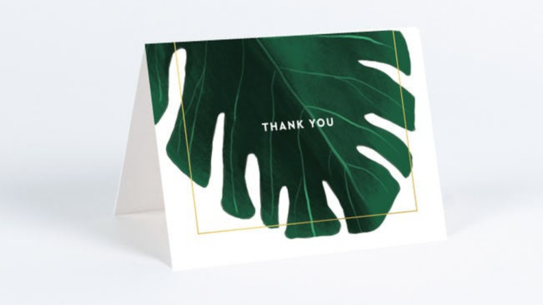 A thank you card with gold font and a green monstera leaf on the front.