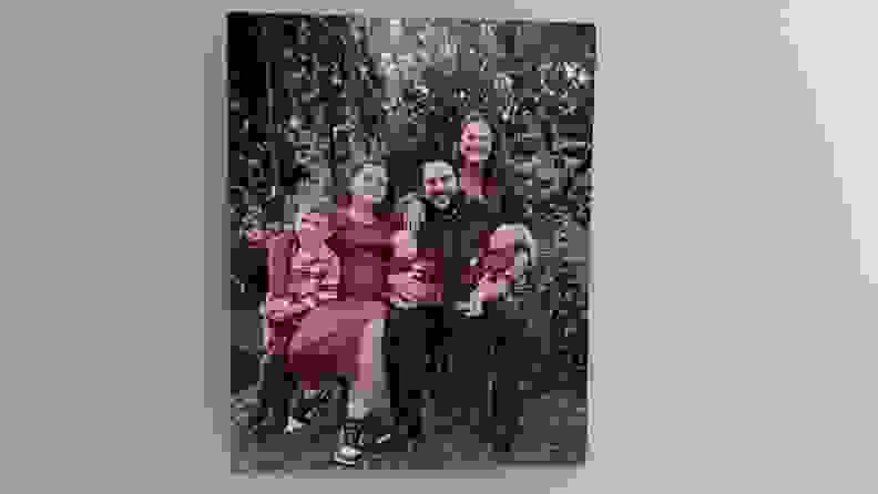 A metal photo print by Frameology showing a family of six hangs on a light gray wall
