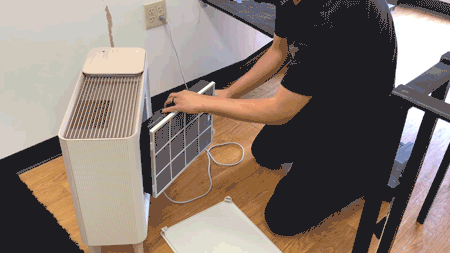A person changing the filter of the air purifier.